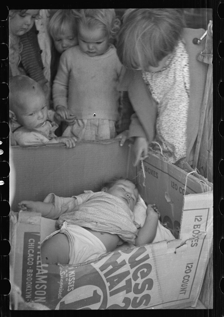 Dorothea Lange, 1936 — a baby asleep in a candy carton at the FSA migrant camp nursery