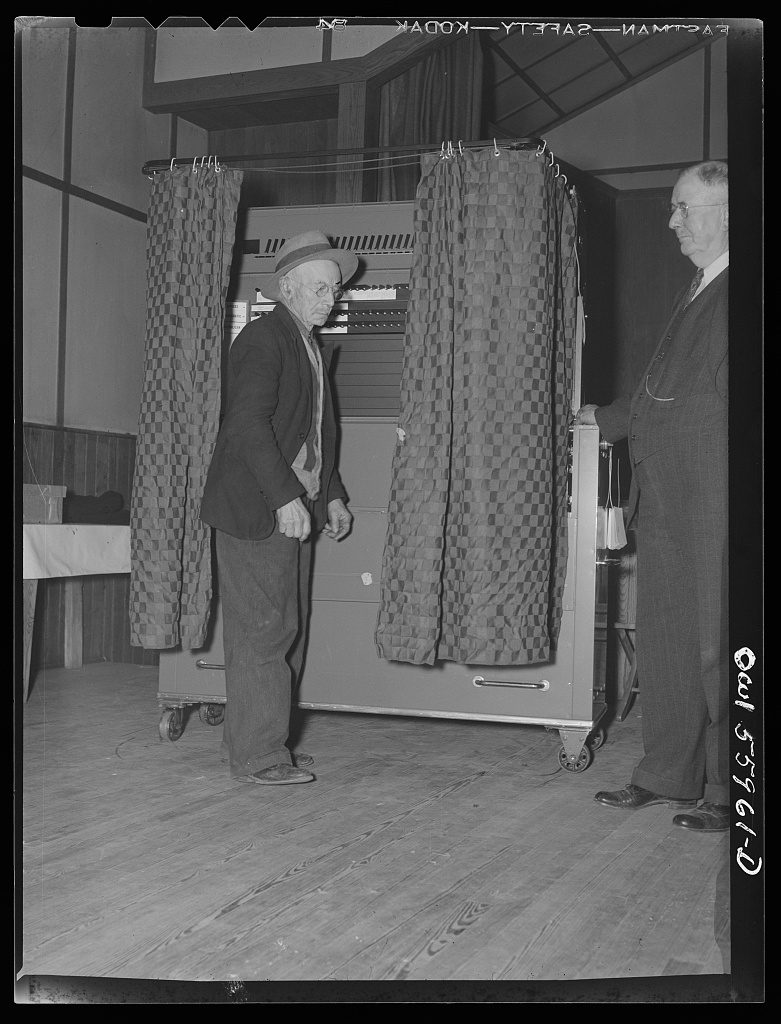 Lewis Walker, Office of War Information, 1944 — a man steps out from a voting booth in Barnesville