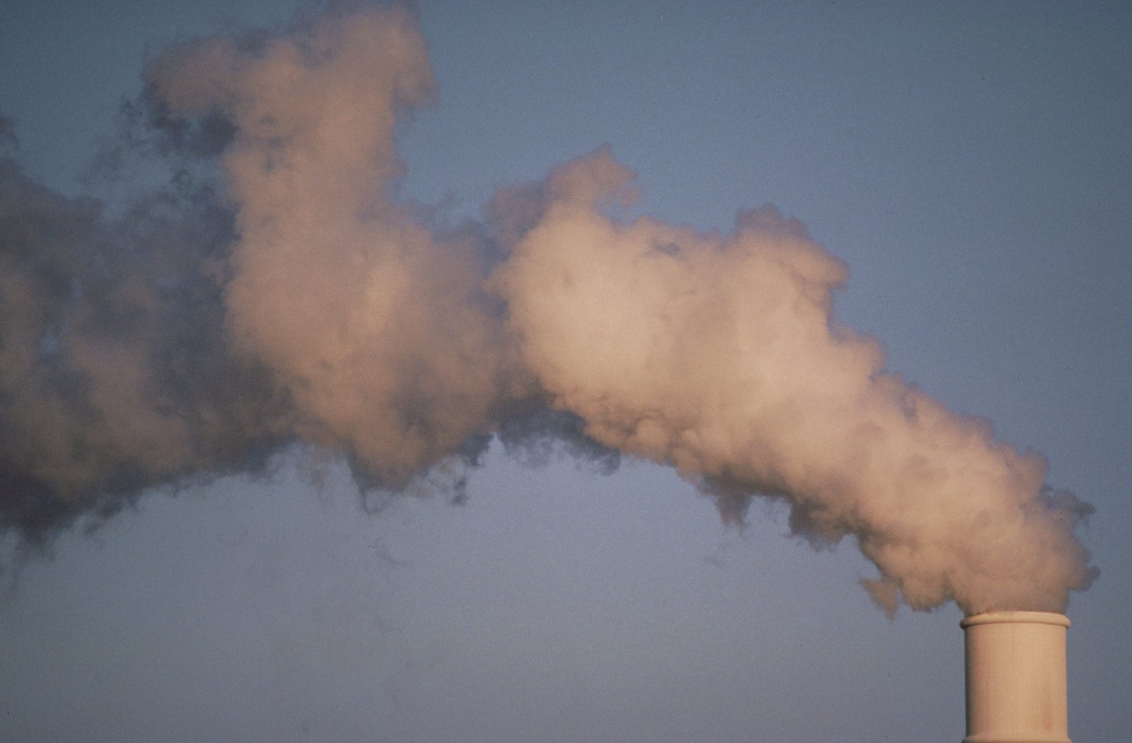 Industrial smokestack emissions against a blue-gray sky